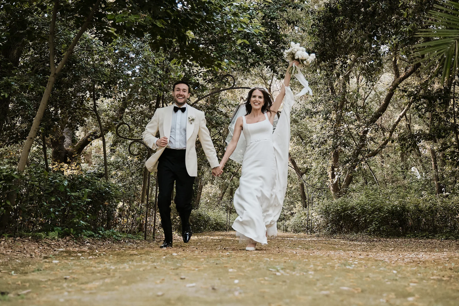 Alex and Daisy celebrating as they walk out among the trees in the Villa Zaira garden