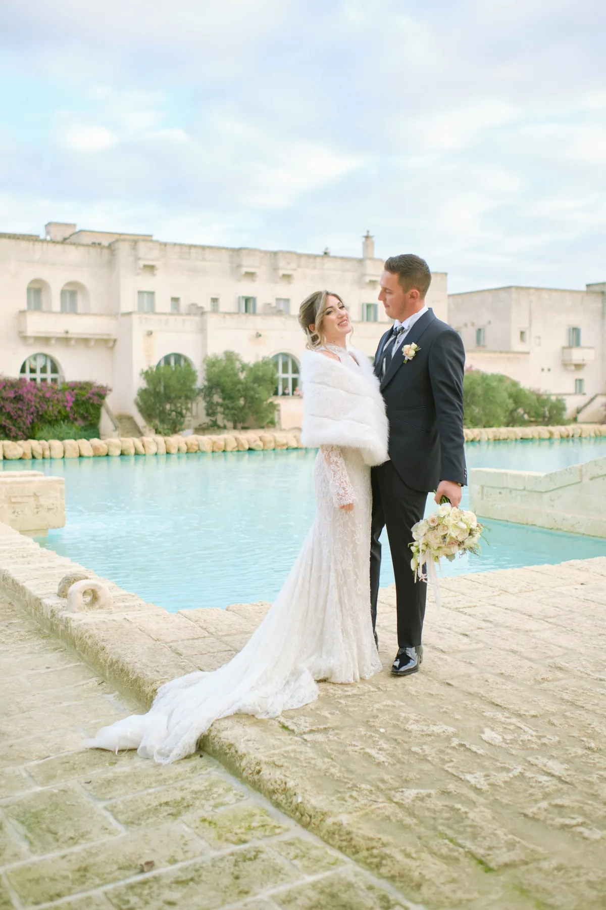 Gli sposi davanti alla piscina e alla facciata del resort
