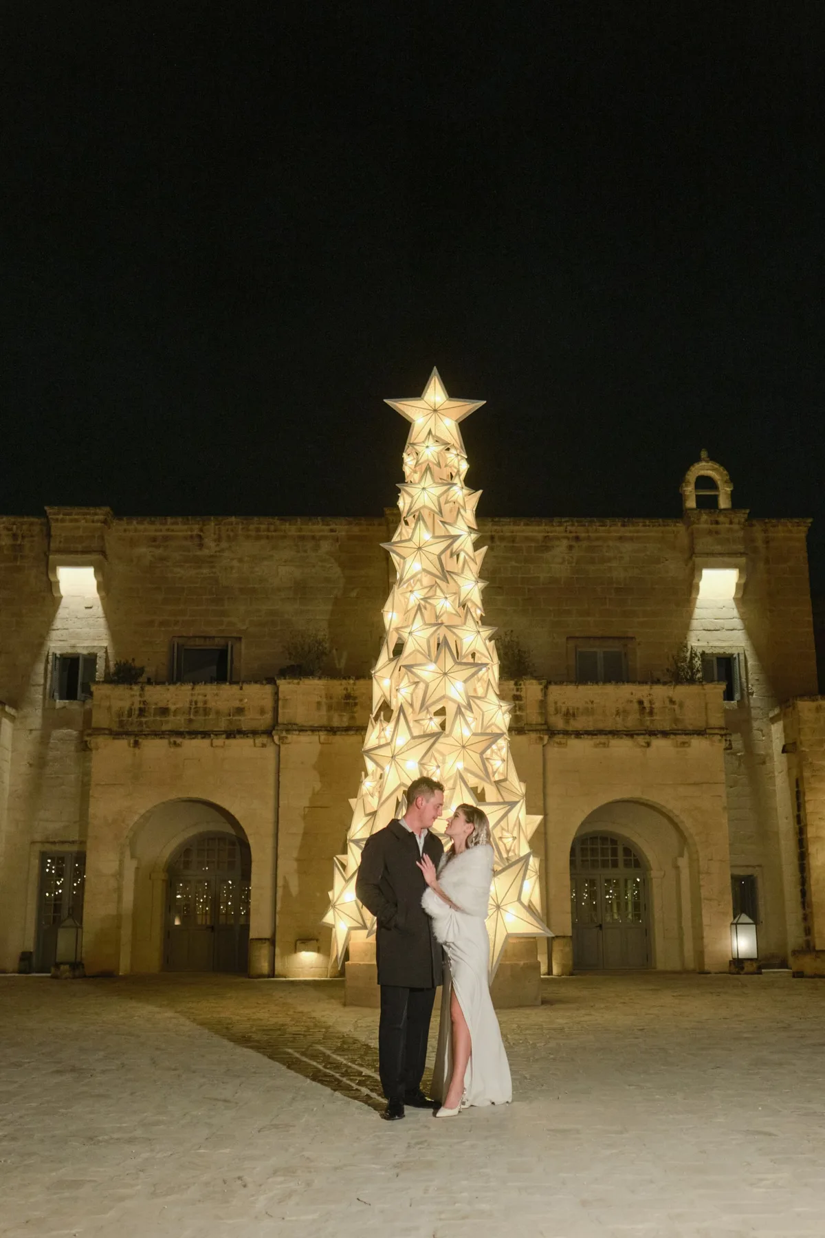 Gli sposi di notte davanti all'albero di Natale illuminato nella piazza
