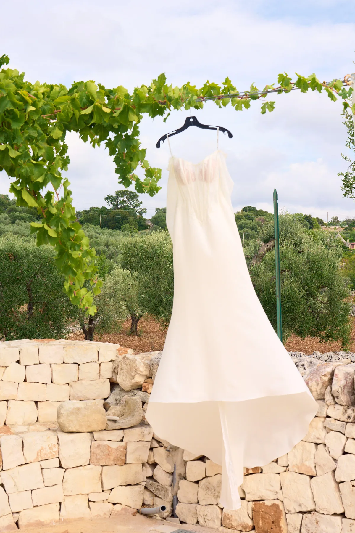 The wedding dress hanging from the pergola above the dry-stone wall