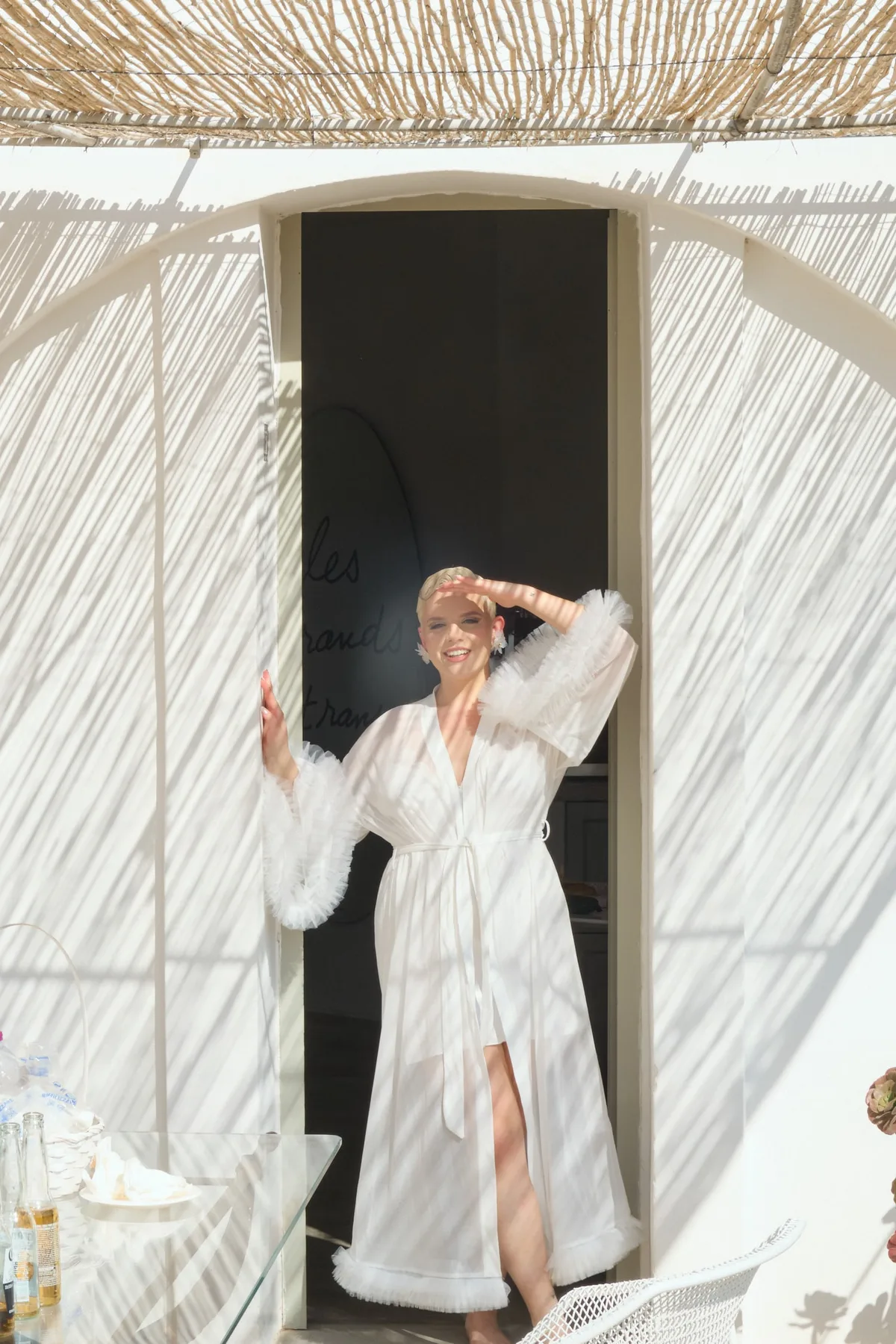 Natasha in her robe at the door, under the reed pergola
