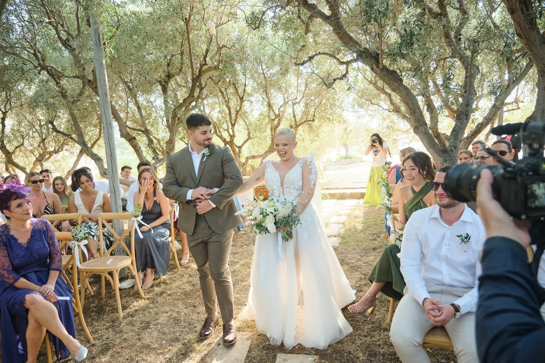 The bride's entrance among the guests in the olive grove