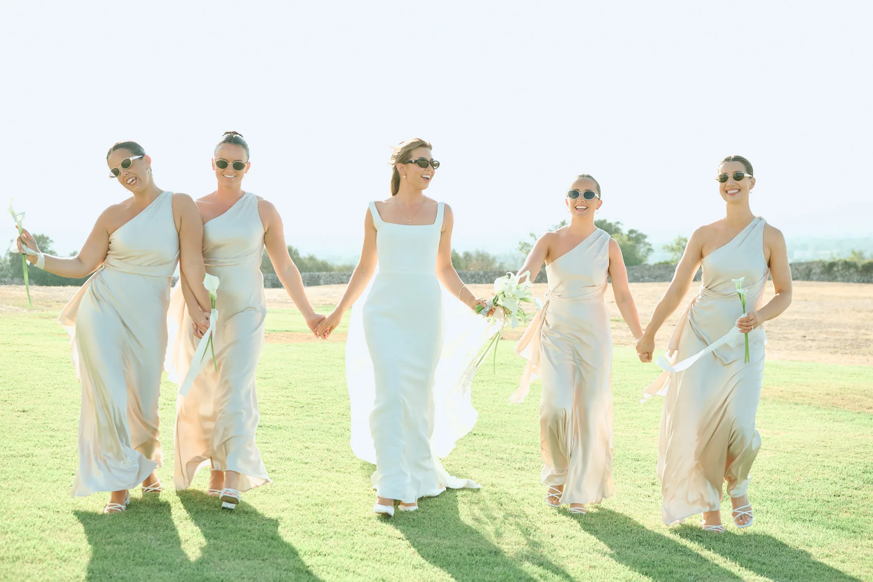 The bridesmaids walking hand in hand on the lawn