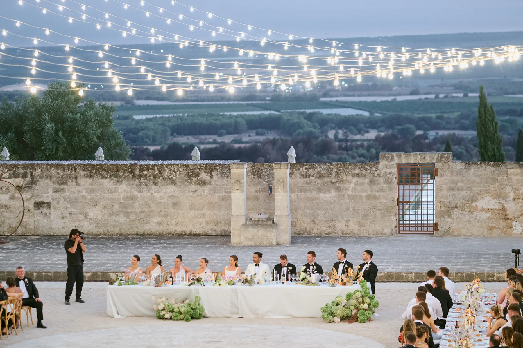 Dinner under string lights, with the countryside at dusk