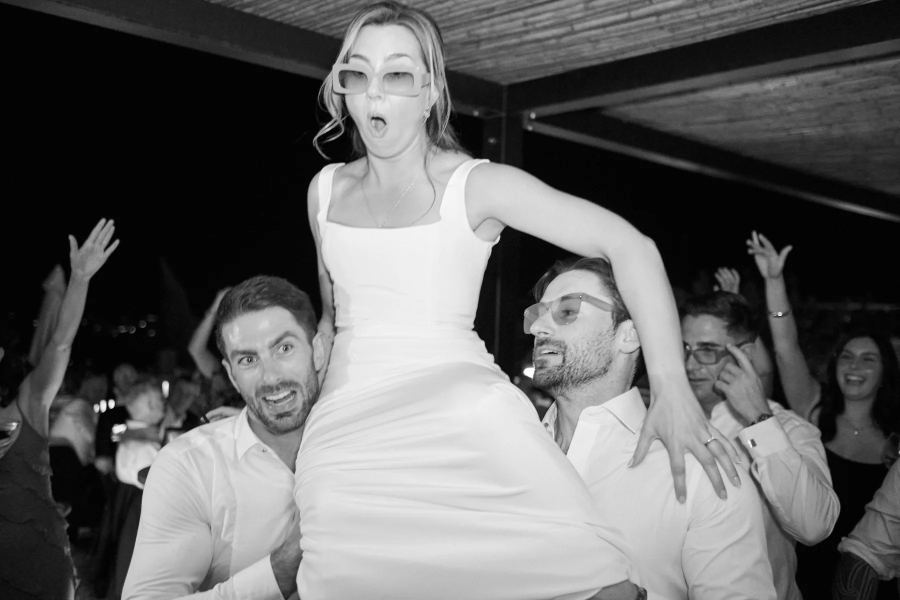 The bride lifted by friends during the party, in black and white