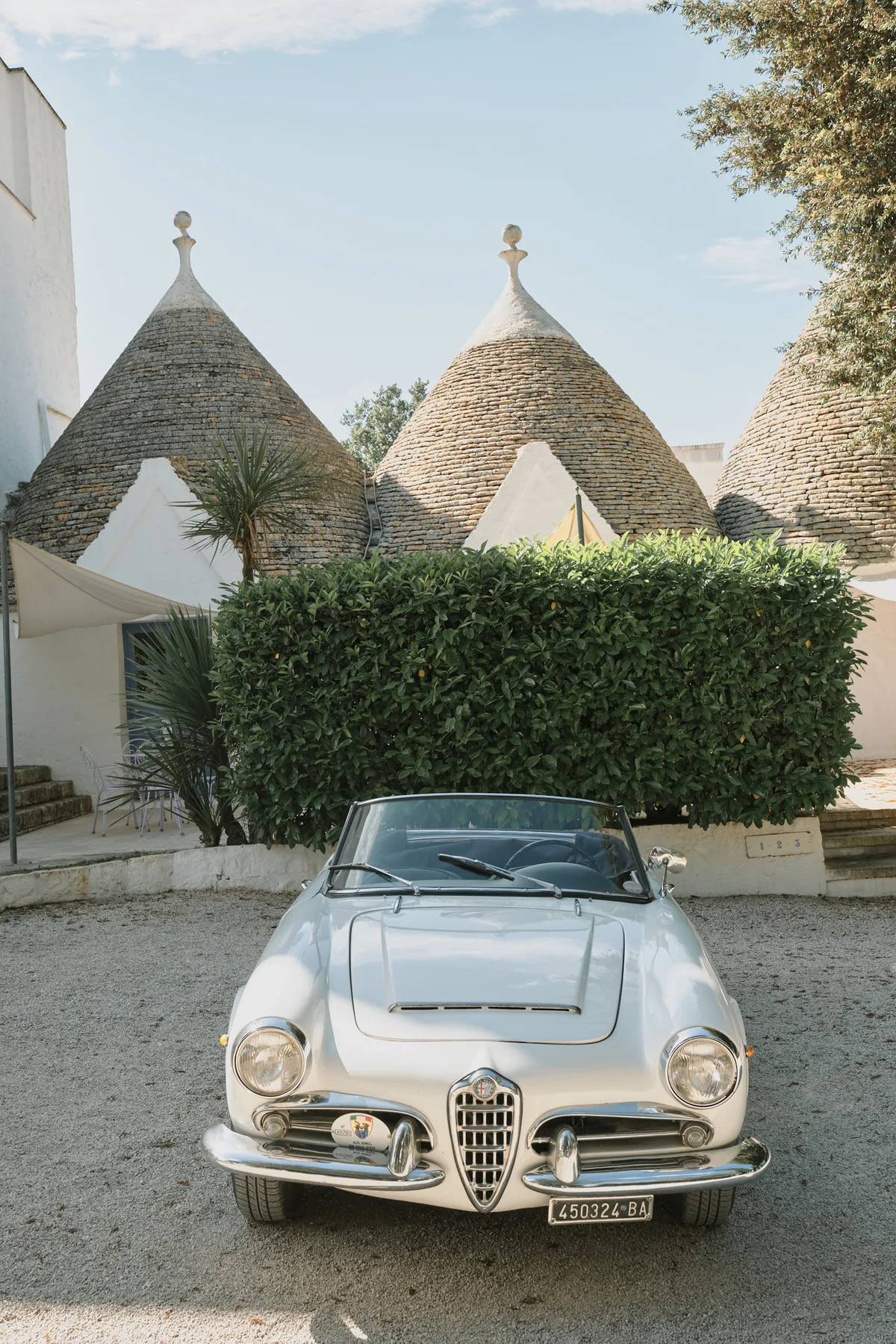 Un’auto d’epoca bianca parcheggiata davanti ai trulli