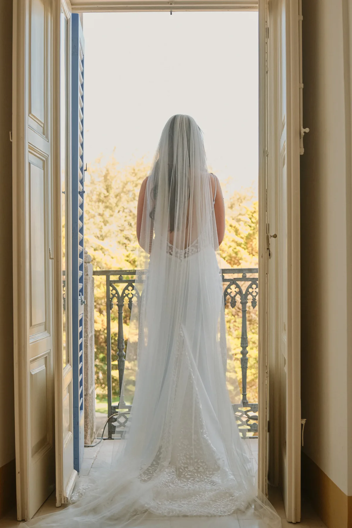 La sposa di spalle sulla porta-finestra, con il velo lungo