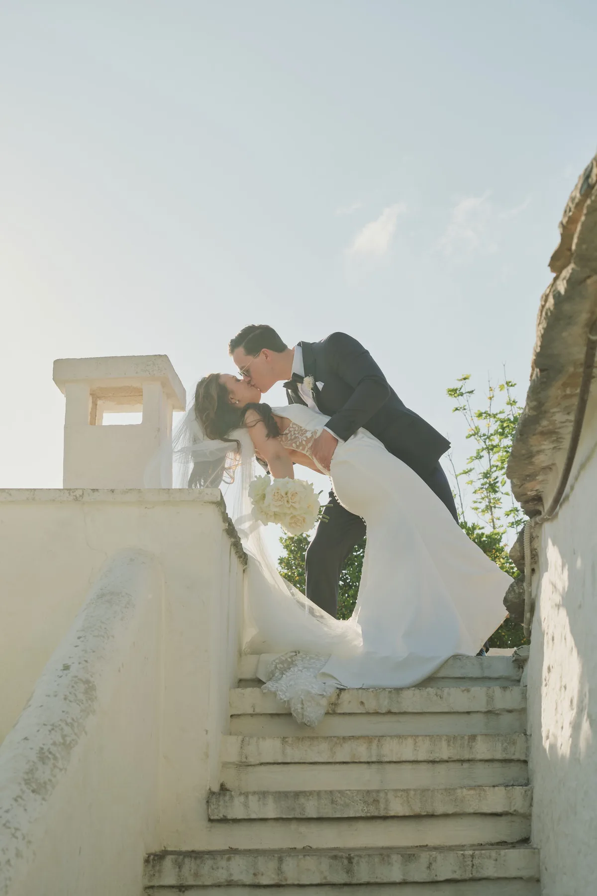 Il bacio degli sposi sulle scale bianche accanto ai trulli