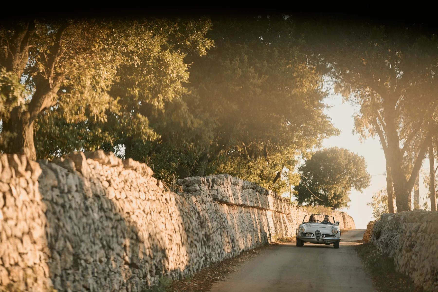 L’auto tra i muretti a secco nella luce dorata del tramonto