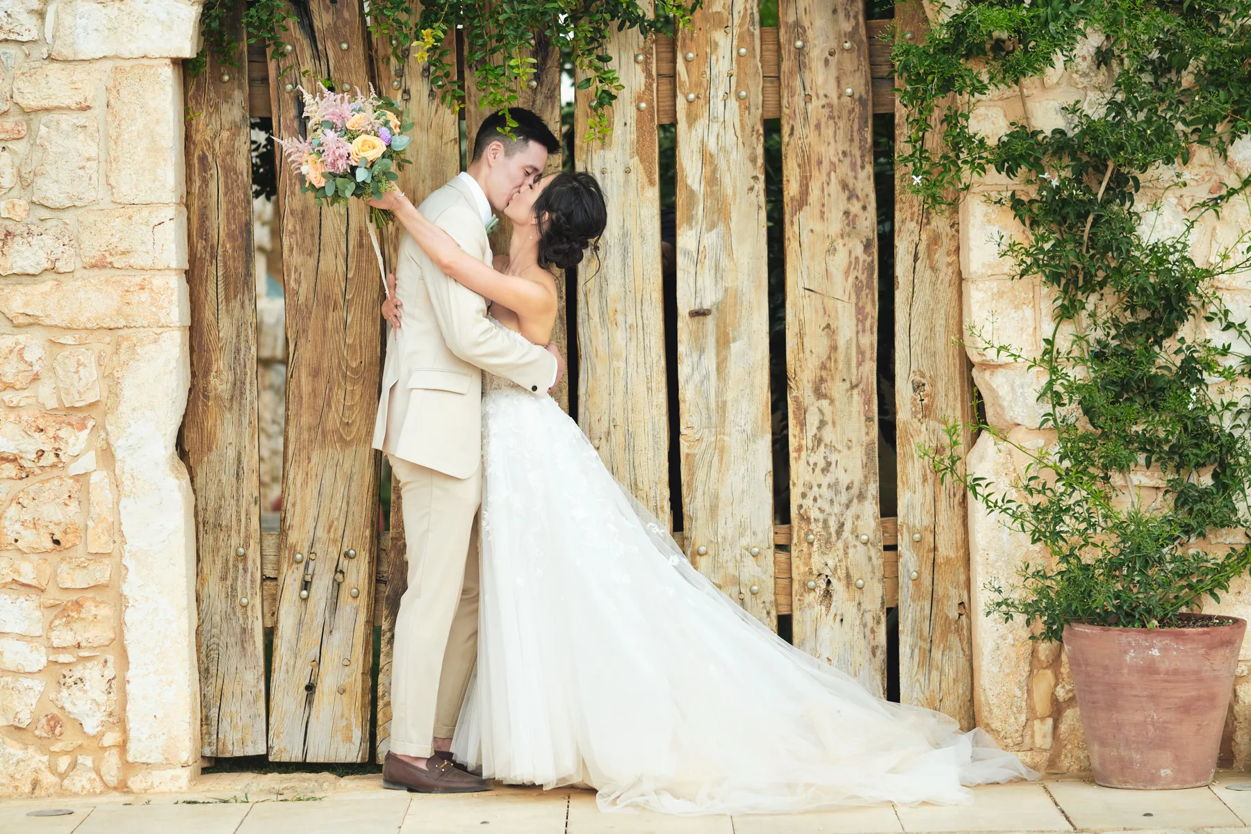 Stef and Sead kissing in front of an old wooden door at the masseria