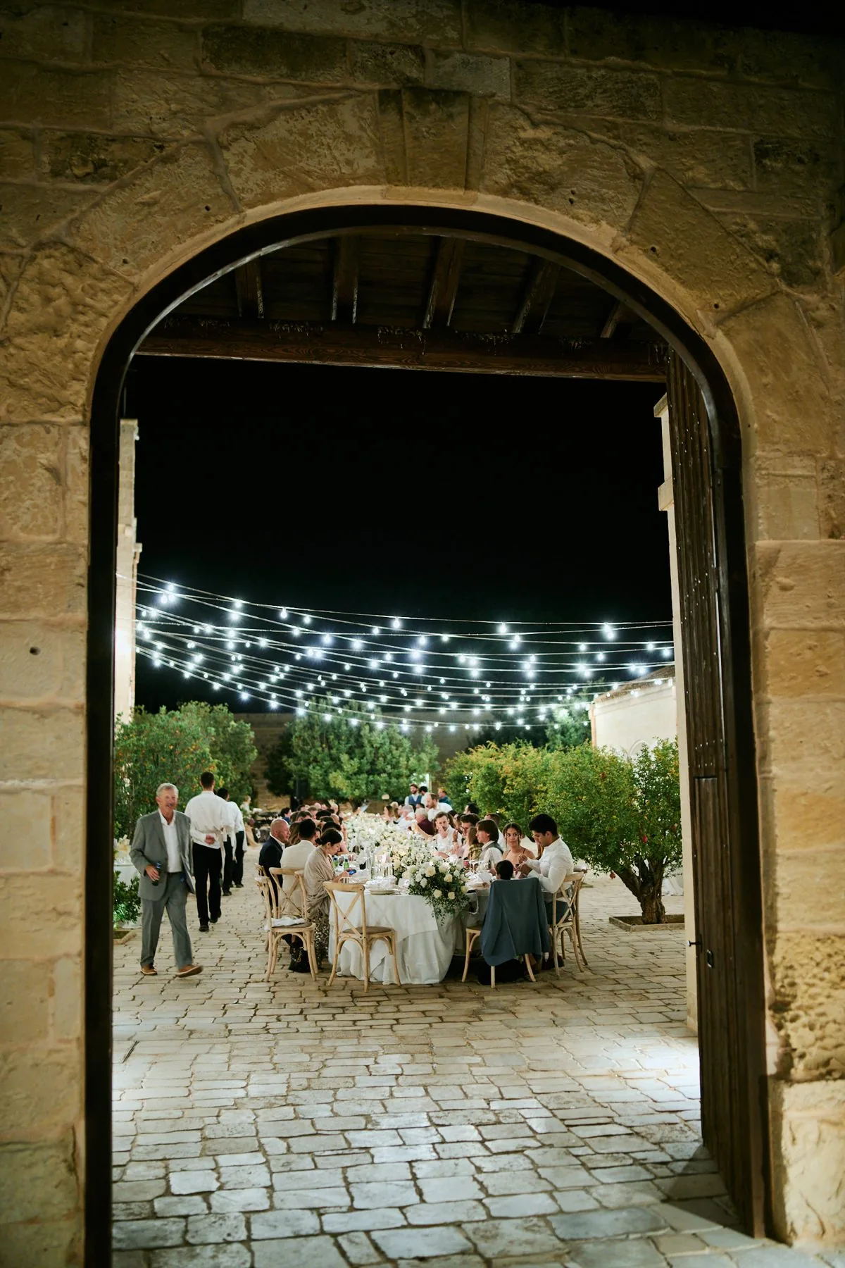 L'ingresso ad arco di Masseria Lilei illuminato per il ricevimento, con le tavolate sullo sfondo