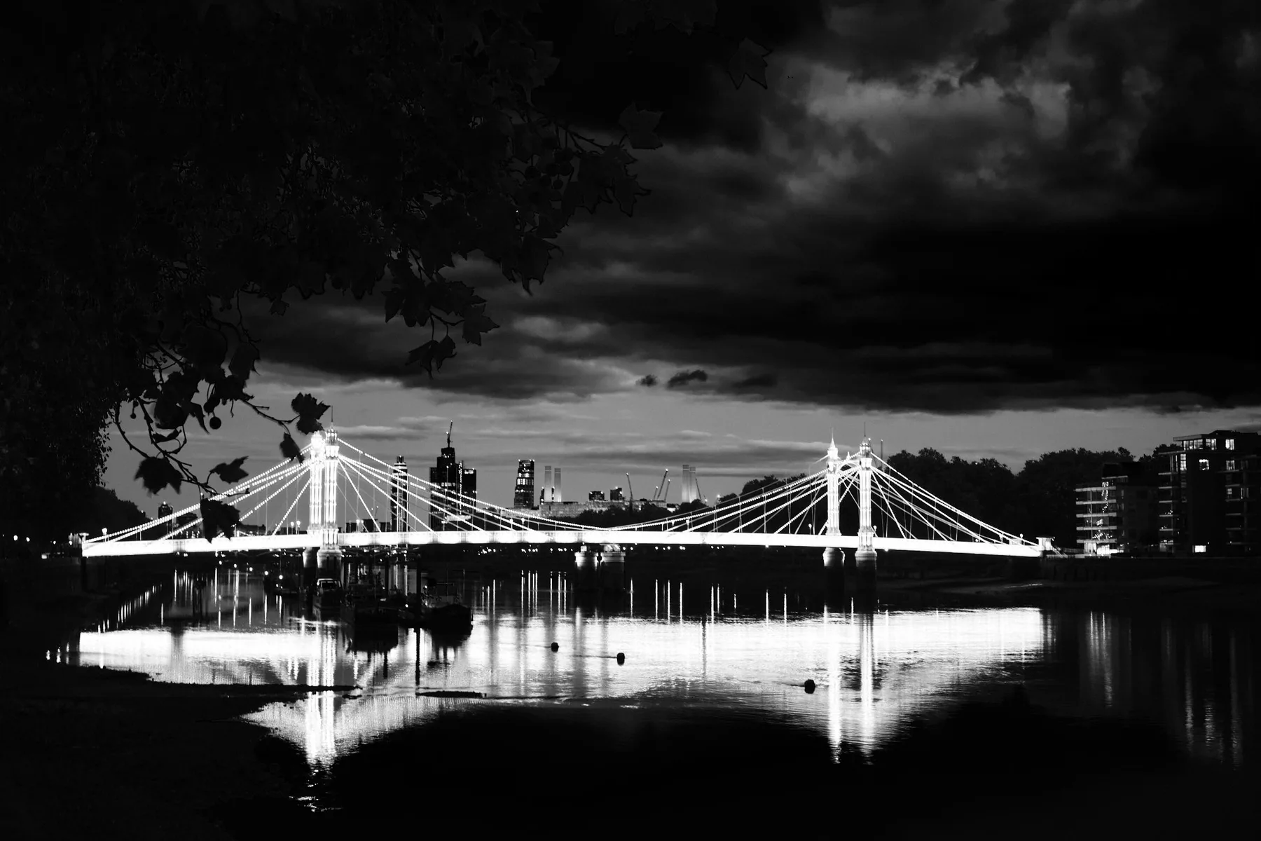 L'Albert Bridge illuminato di notte sul Tamigi, sotto un cielo di nuvole