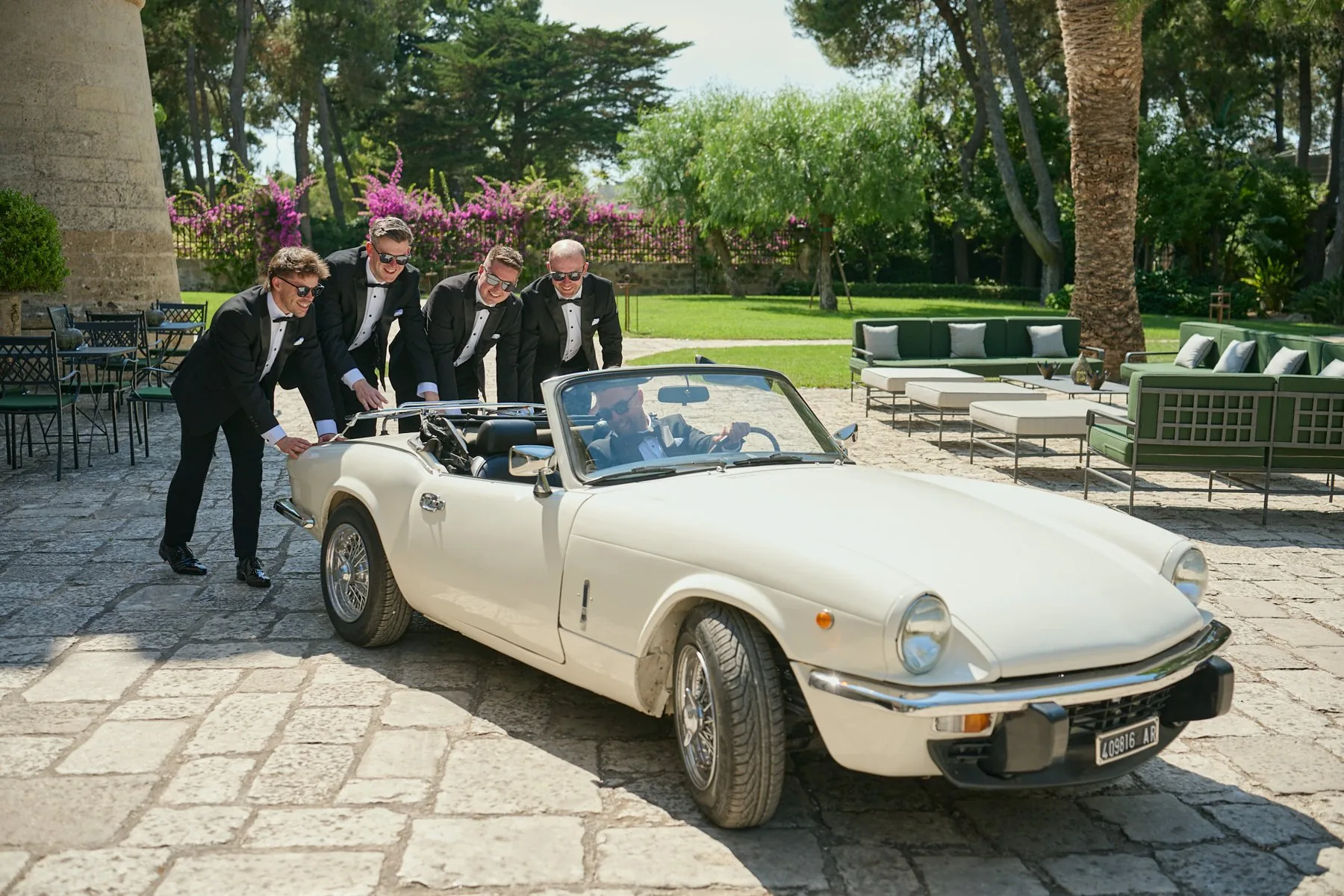 I testimoni spingono l'auto d'epoca, scherzando con lo sposo alla guida