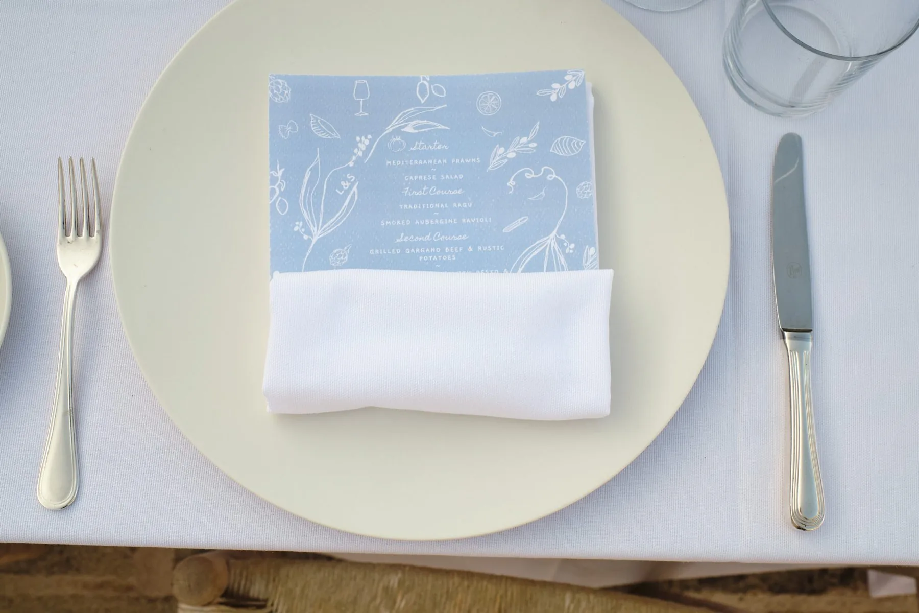 Dettaglio della mise en place, con tovagliolo blu decorato